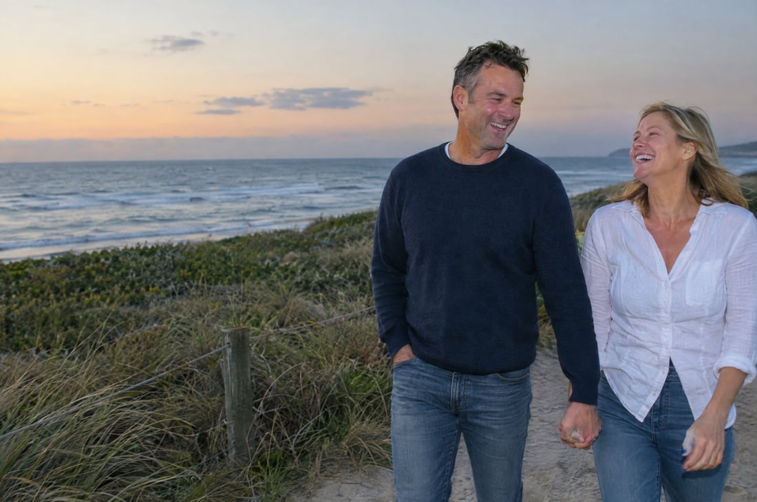 A couple walking hand in hand along a beach path at dusk