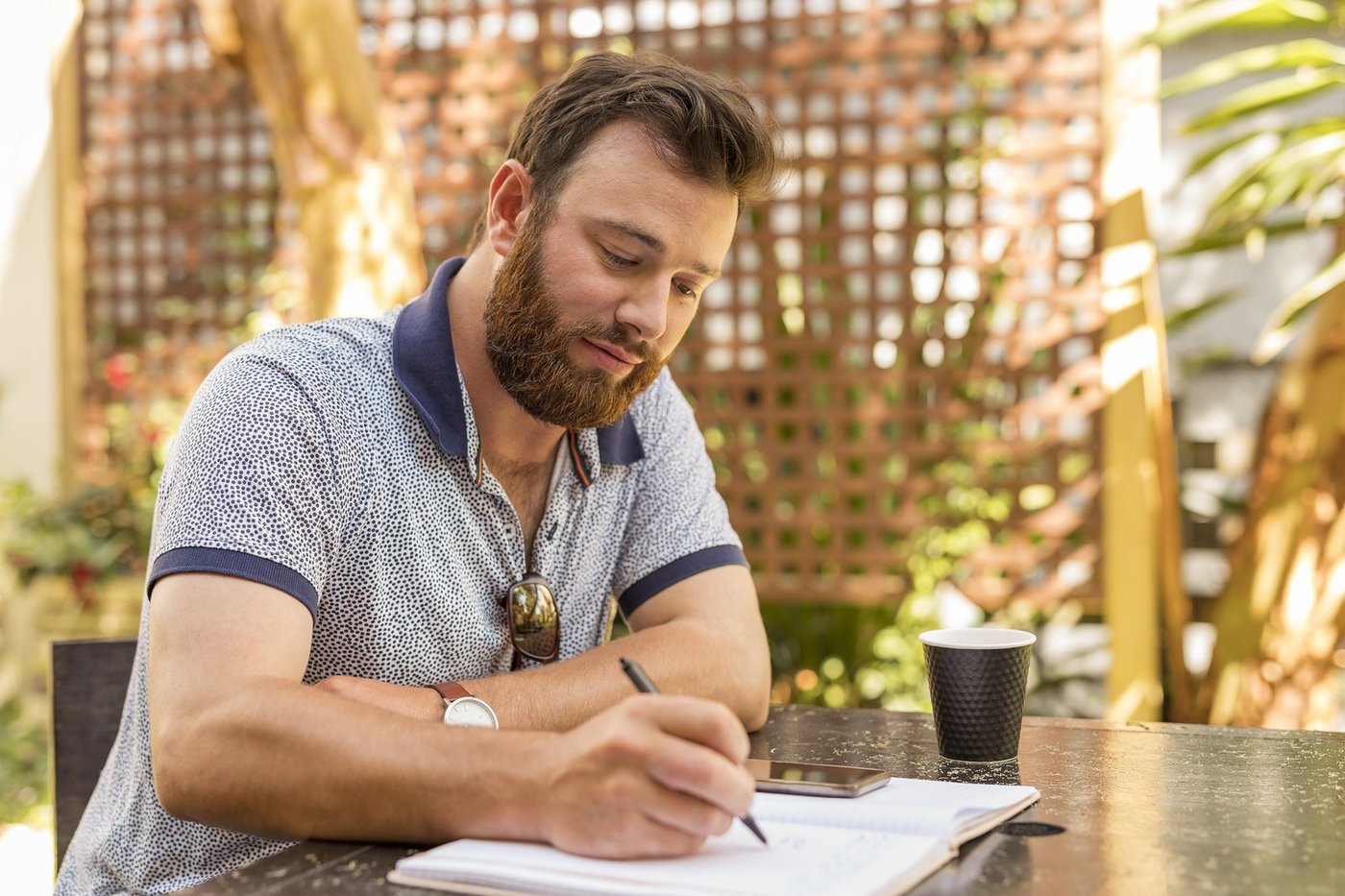 A man taking notes at an outdoor cafe table