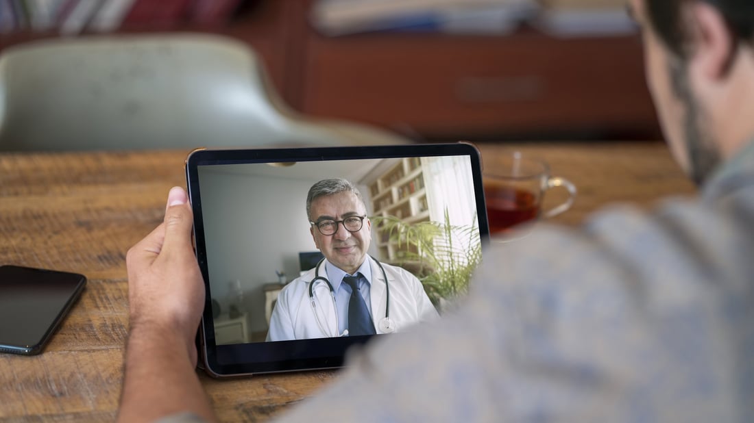 A man on a video call with a doctor on his tablet