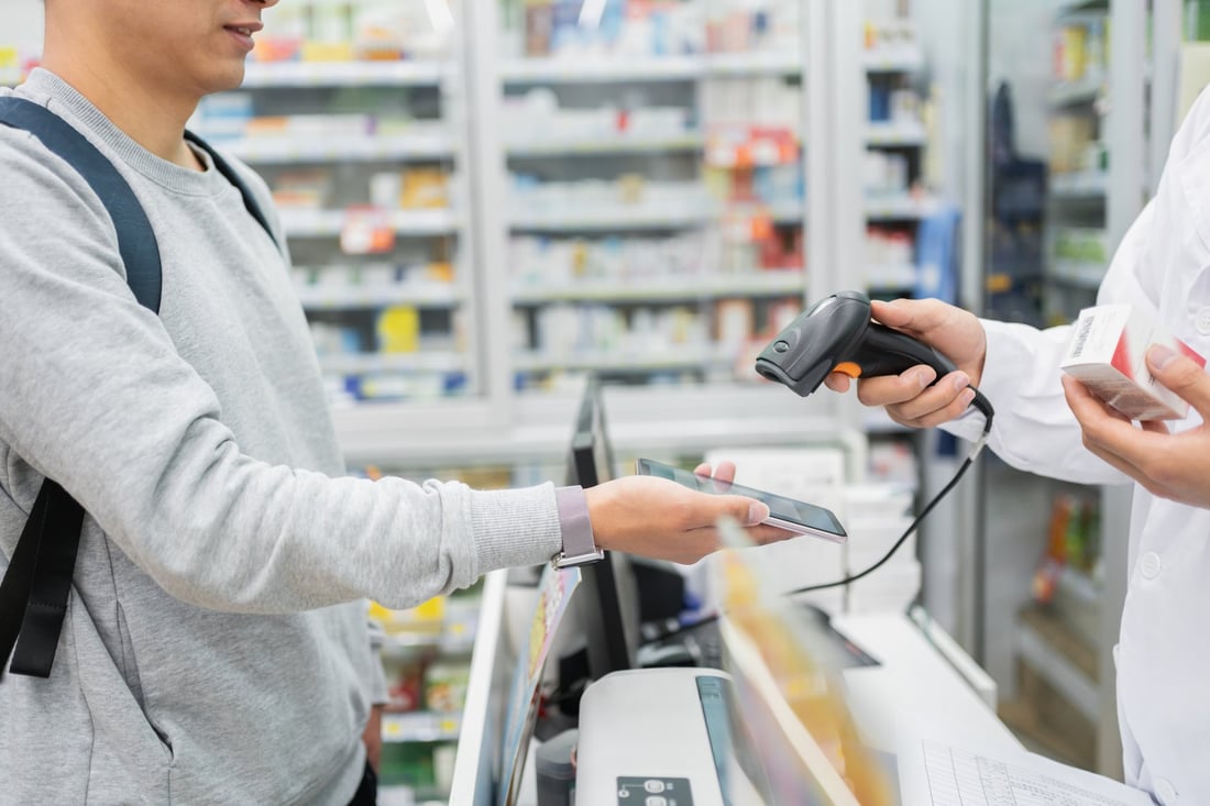 A man showing his eScript on his phone at a pharmacy counter
