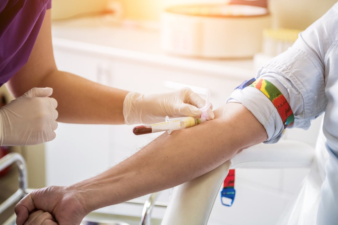 A nurse taking a blood sample from a patient's arm