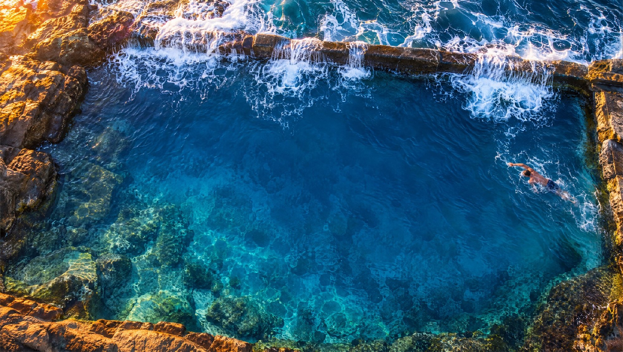 Aerial view of a man swimming in an ocean rock pool